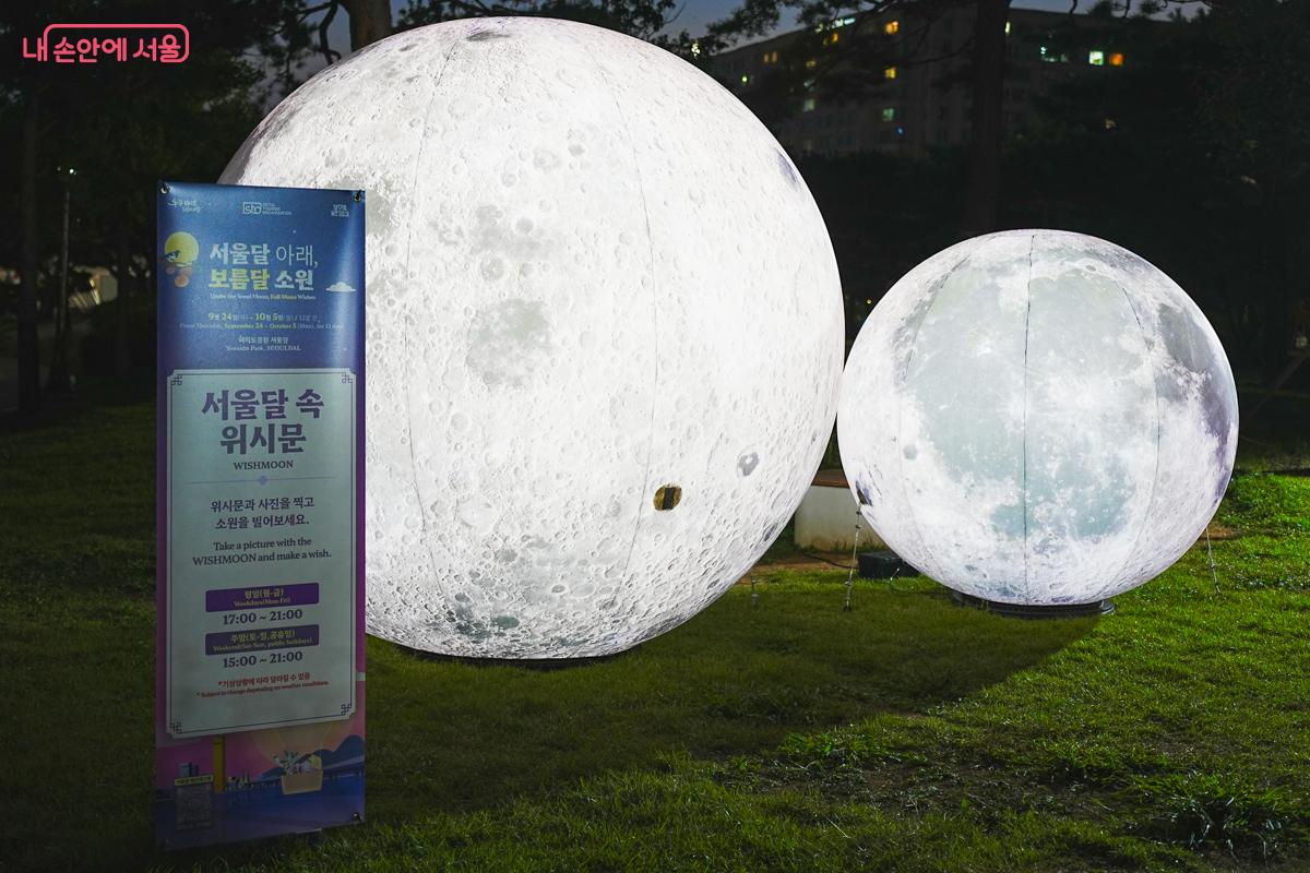 지름 3m와 2m 크기의 대형 보름달 조형물 두 개와 '서울달 속 위시문 WISHMOON' 안내판, 운영시간이 적혀 있다.