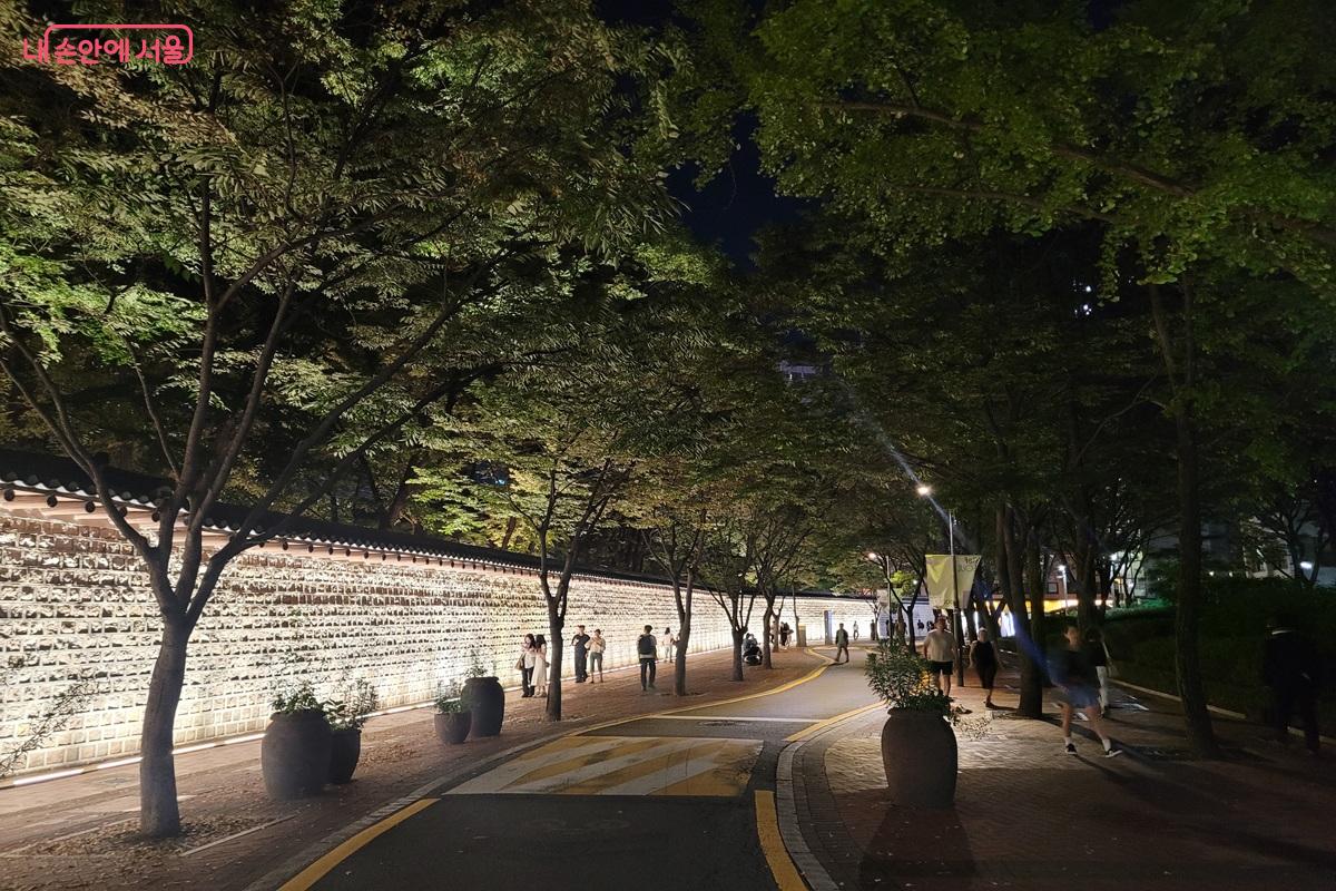 야간 조명이 켜진 덕수궁 돌담길을 걷는 시민들 ©조연
