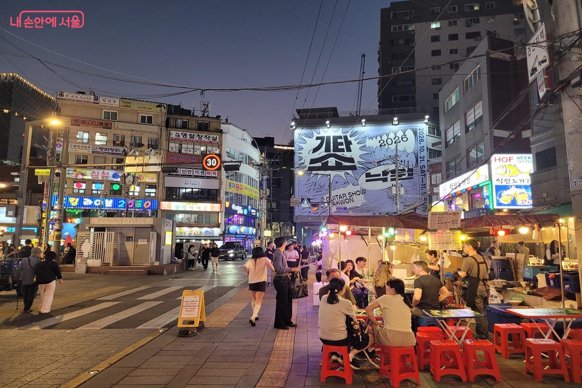 불을 밝힌 종로3가 포장마차의 테이블에 여러 방문객이 앉아 있는 밤 풍경 &copy;조연