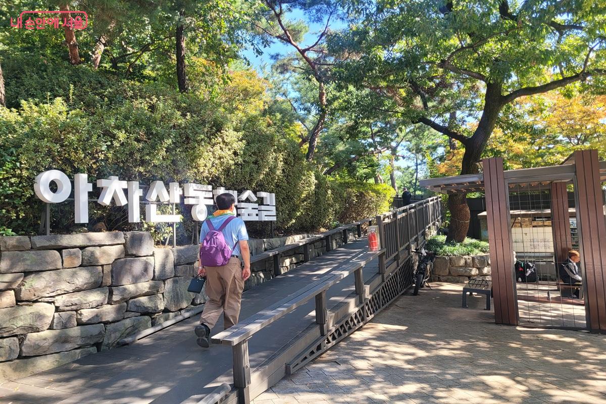 아차산 동행숲길 글자가 있는 돌담 옆으로 이어지는 나무 데크 진입로