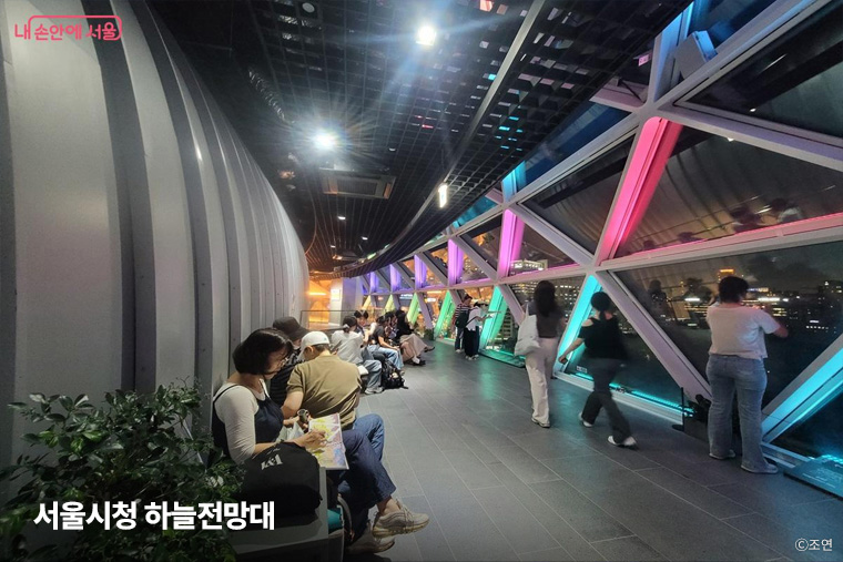 서울시청 하늘전망대 창가에서 서울의 밤 풍경을 감상하고 있다. 