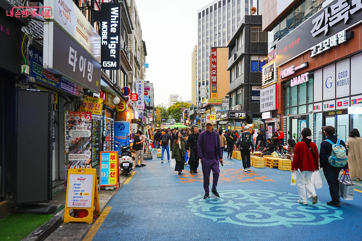 파란색으로 포장된 보행자 거리에 상점 간판이 늘어서 있고 시민들이 오가는 모습, 러시아어·몽골어 간판이 눈에 띈다.