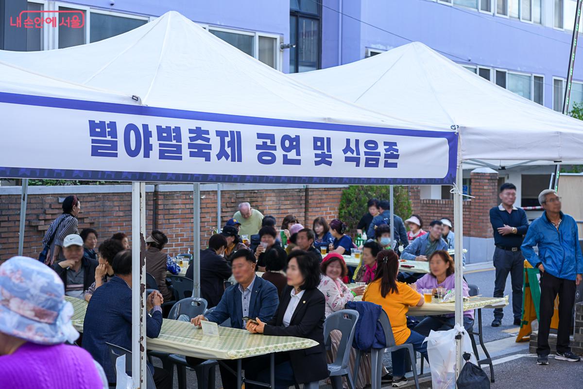 '별야별축제 공연 및 식음존' 배너가 걸린 텐트 아래, 테이블마다 둘러앉아 식사하고 대화하는 방문객들