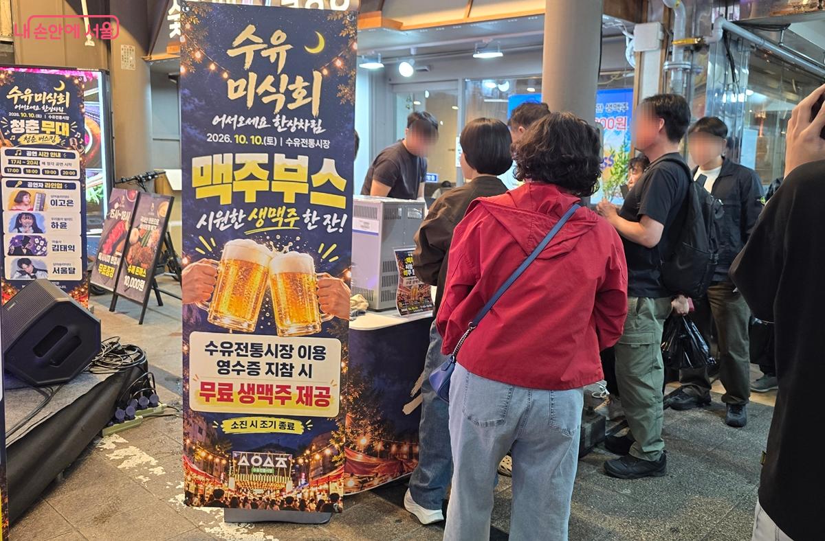 시장 이용객들이 영수증을 보여주고 무료 생맥주를 받기 위해 줄을 서고 있다. &copy;조성희