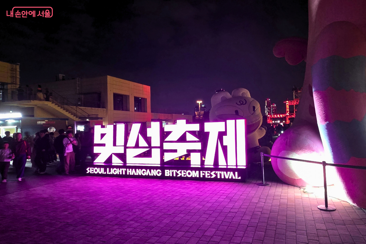 밤이 된 노들섬 축제장 입구에 ‘빛섬축제’라고 적힌 대형 조형물이 분홍빛으로 환하게 빛나고 있다.