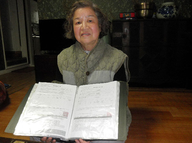 빼곡하게 모아둔 후원 영수증 파일을 들고 있는 김진순 할머니