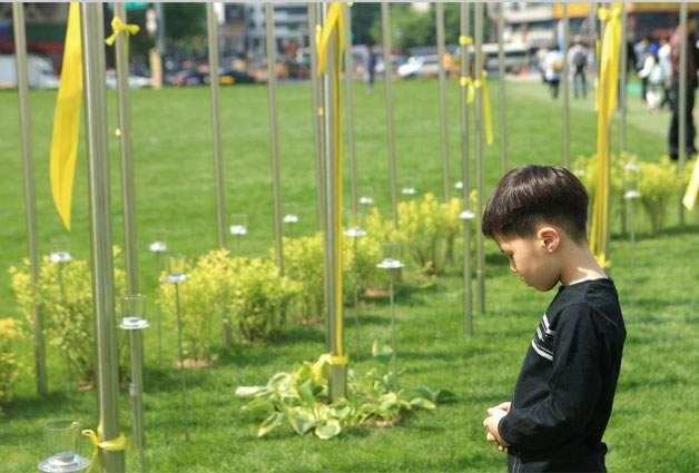 작년 5월 `노란 리본의 광장`을 찾은 아이가 고인들의 명복을 빌고 있다