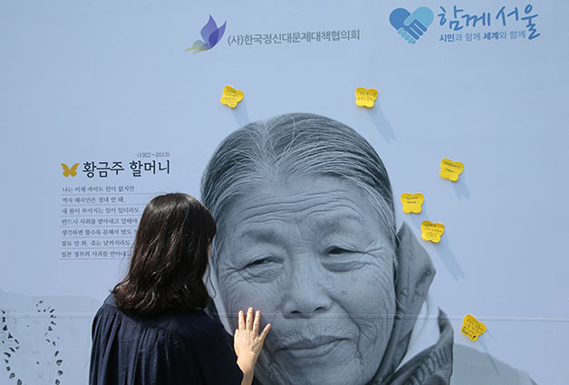 일본군 위안부 할머니 세 분의 사진 아트월에 한 시민이 응원 메시지를 붙이고 있다