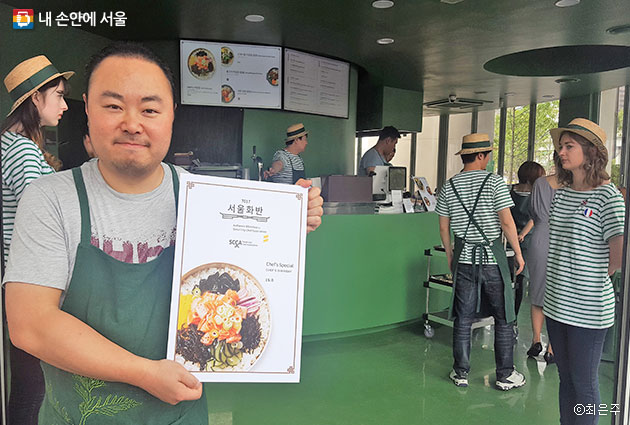 `7017서울화반`에서 김훈이 쉐프가 비빔밥 메뉴판을 들고 있다. ⓒ 최은주