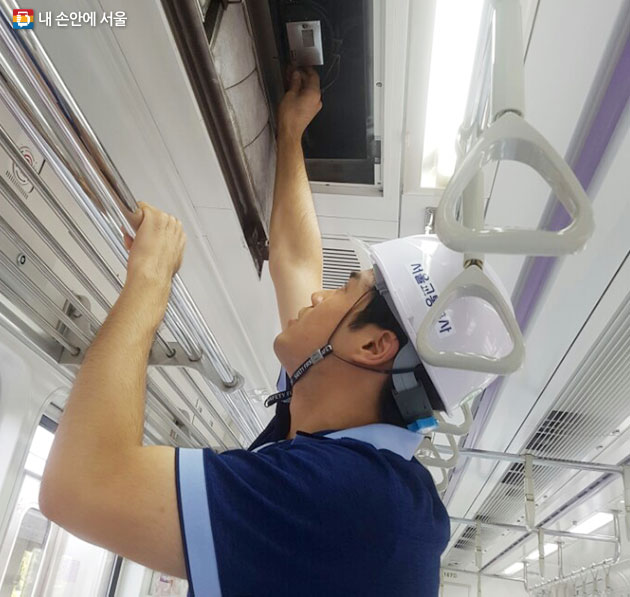 서울교통공사 직원이 객실 천장에 있는 냉방기의 온도를 조절하고 있다