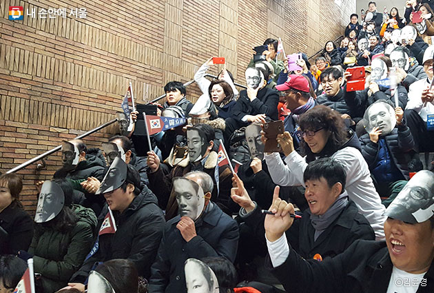 김구, 안중근, 유관순 등 독립운동가의 마스크를 쓴 시민들이 안국역 승강장에서 '대한독립만세 태극기'를 흔들며 독립군가를 힘차게 부르고 있다.