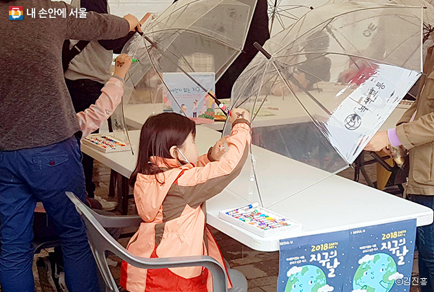 우산에 미세먼지 없는 하늘 그리기에 열중하고 있는 어린이