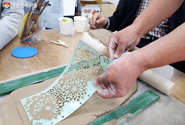 50+남부캠퍼스 도예 체험 수업 중 수강생이 찰흙을 밀어 무늬를 만들고 있다.