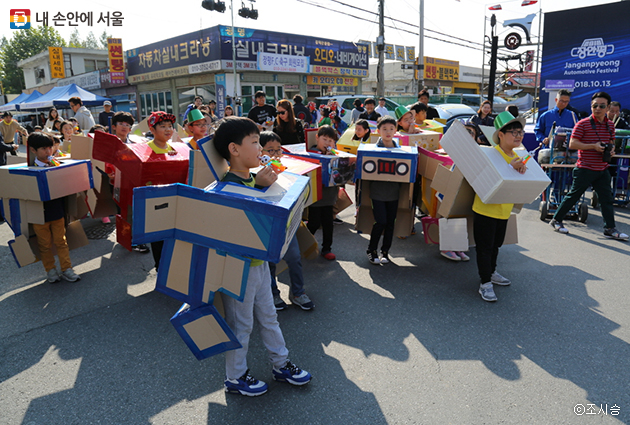 지역관내 초등학생들이 스스로 제작한 모형자동차를 두르고 장안평 행사장 자동차거리를 행진하고 있다.