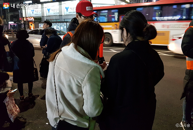 여성승객들이 승차지원단의 도움으로 티맵택시 활용방법을 배우고 있다