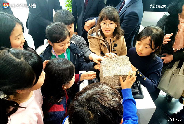‘돌의 귀환’ 행사에 참석한 아이들이 ‘서울 돌’을 만지며 신기해 하고 있다