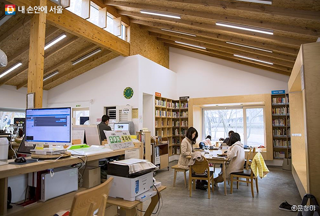 도서관 큰 창을 통해 숲을 바라볼 수 있는 삼청공원 숲속 도서관의 여유로운 분위기