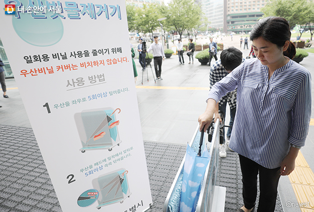 서울시청 정문에서 친환경 우산 빗물제거기 사용하는 시민