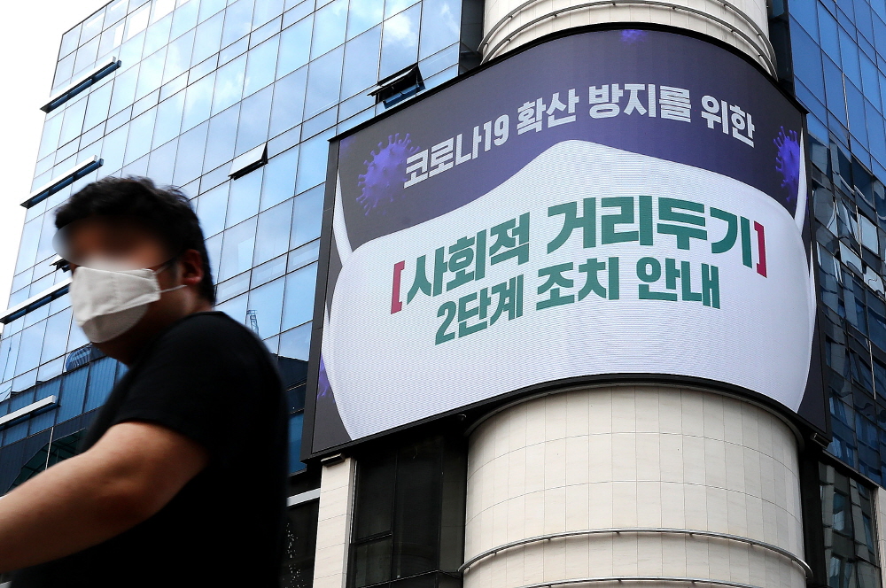명동거리에서 한 시민이 전광판에 나오는 마스크 쓰기 캠페인 화면 앞을 지나고 있다.