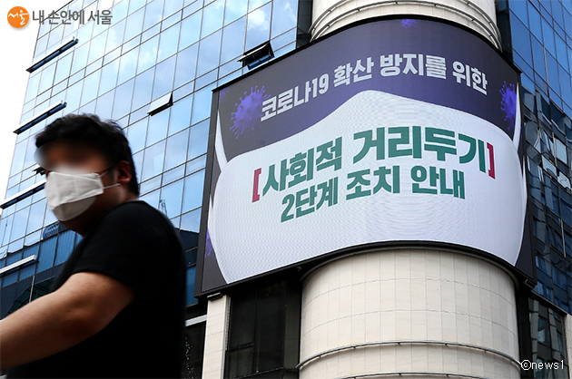 서울 중구 명동거리에서 한 시민이 전광판에 나오는 마스크 쓰기 캠페인 화면 앞을 지나고 있다. 