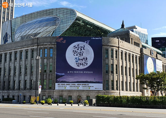 서울도서관 외벽에 “더도 말고 덜도 말고 집에만 있어라”라는 메시지를 담은 포스터가 붙어있다
