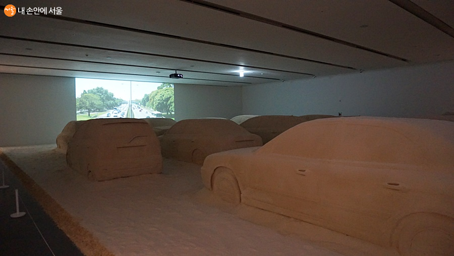 13대의 자동차를 모래로 만들어낸 설치미술 작품, 실제로는 달릴 수 없는 모래자동차의 이룰 수 없는 꿈을 보여주는 작품이다