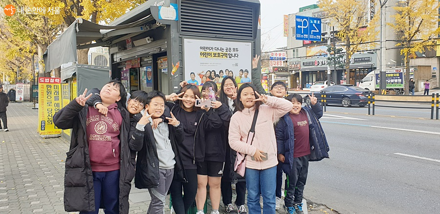 구두 가판대에 게재된, 자신들이 직접 참여한 '어린이 보호구역' 희망광고를 기념하고 있는 아이들 