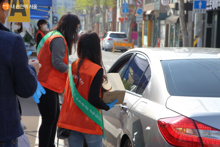 자원봉사자들이 드라이브스루 구매를 돕고 있다.