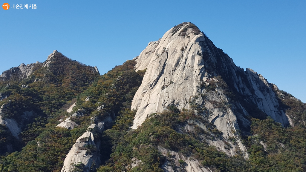 등산로 영봉코스에서 바라본 인수봉, 깎아지른 듯한 절벽을 따라 암벽등반가들이 매달려 있다.