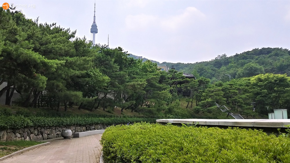서울천년 타임캡슐 뒤로 정자 망북루가 있고 멀리 N서울타워가 보인다.